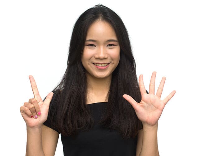 A young Asian woman making a gesture with her hands while discussing group health insurance and employee benefits in Singapore as an insurance broker.