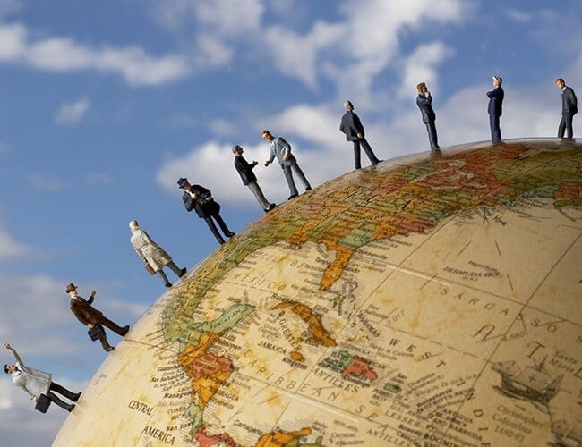 A group of business people standing on top of a globe, discussing group health insurance options with an insurance broker in Singapore.