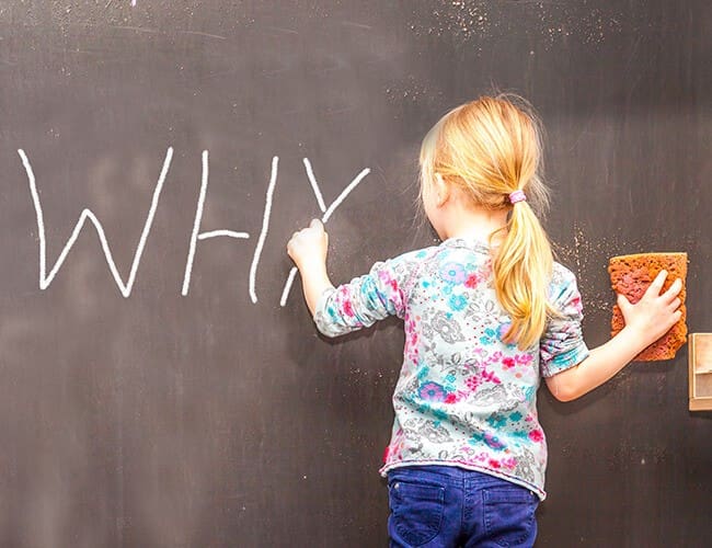 A little girl writing the word "why" on a blackboard, while her parents discuss medical benefits Singapore.