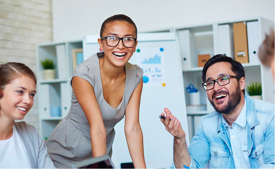 A group of people laughing in an office while discussing their employee benefits with an insurance broker in Singapore.