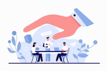 A hand reaching out to a group of corporate insurance brokers sitting at a table.