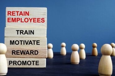 A group of wooden blocks with the words retain employees, motivation, and reward.
