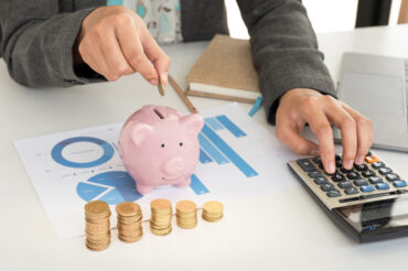 A woman is putting coins into a piggy bank for her employment benefits in Singapore.