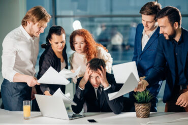 A group of business people gathered around a laptop to discuss employment benefits in Singapore.