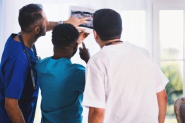 A group of doctors examining an x-ray for medical benefits evaluation.